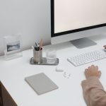 High angle of crop faceless person sitting at table with wireless gadgets and computer