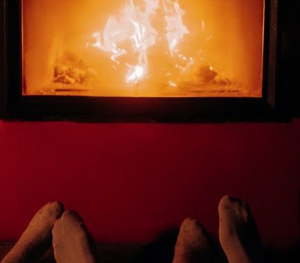 A warm, romantic moment by the fire with cozy socks and gentle lighting.